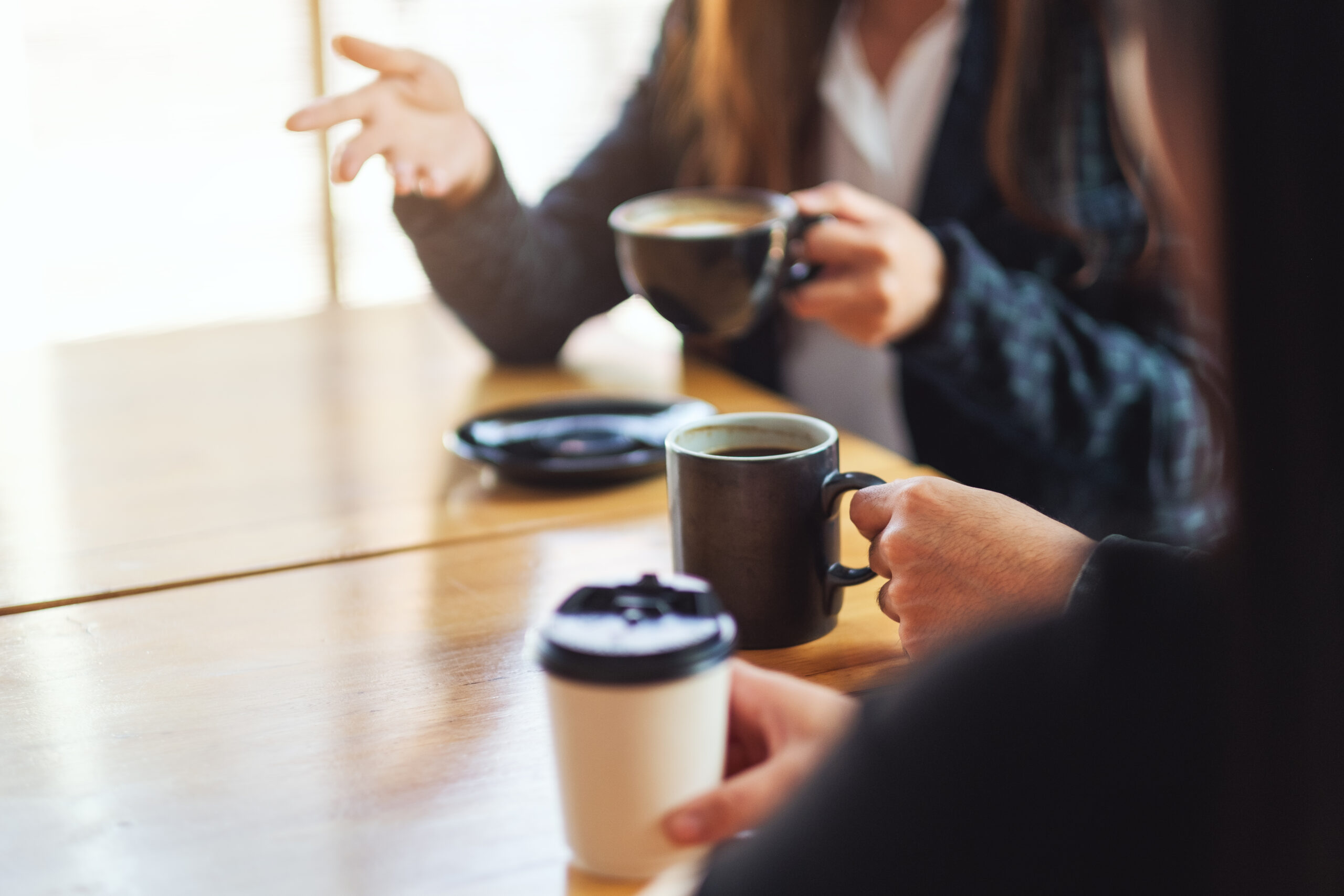 Closeup image of people enjoyed talking and drinking coffee together in cafe